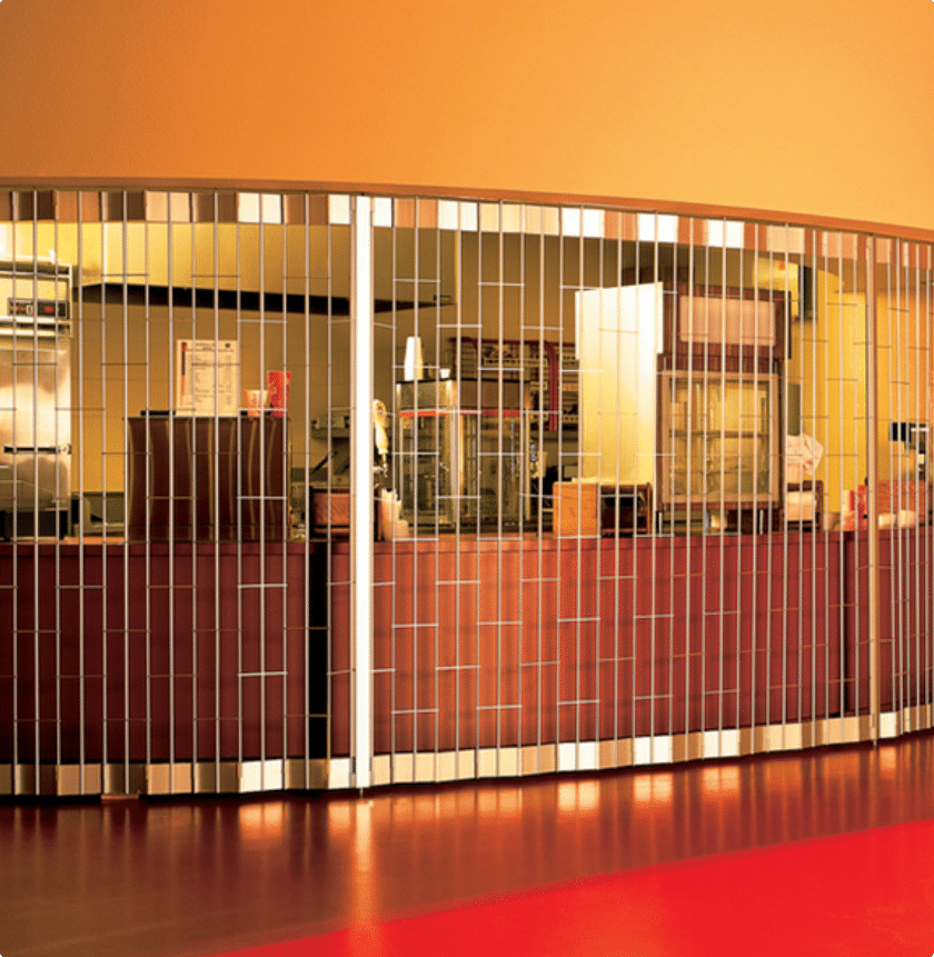 Closed food concession stand with a metal security gate. The counter is behind the gate, with visible kitchen equipment and supplies inside. The floor is red, and the walls are painted in warm tones.