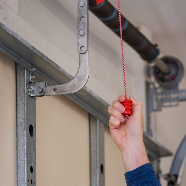 Man pulling manual safety release cord handle before performing maintenance on electric garage door opener
